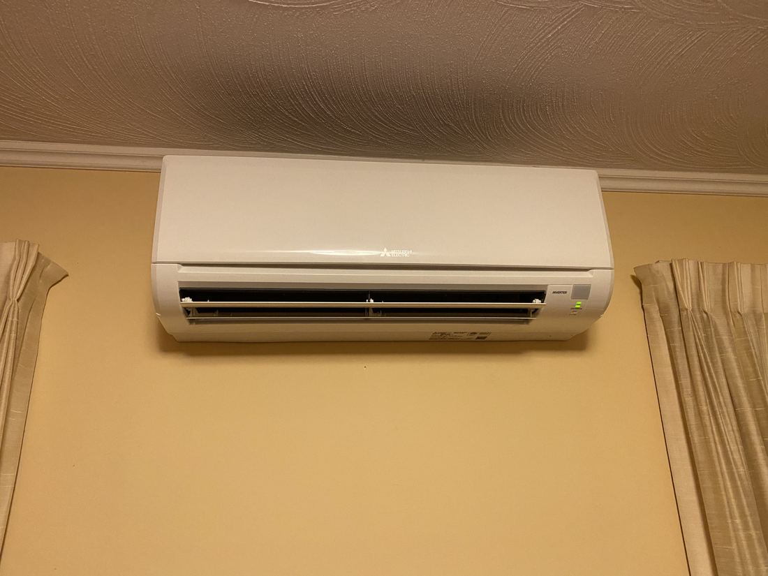 A ductless indoor air handler mounted high on a wall