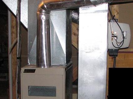 A residential gas furnace in a basement with metal ductwork above it
