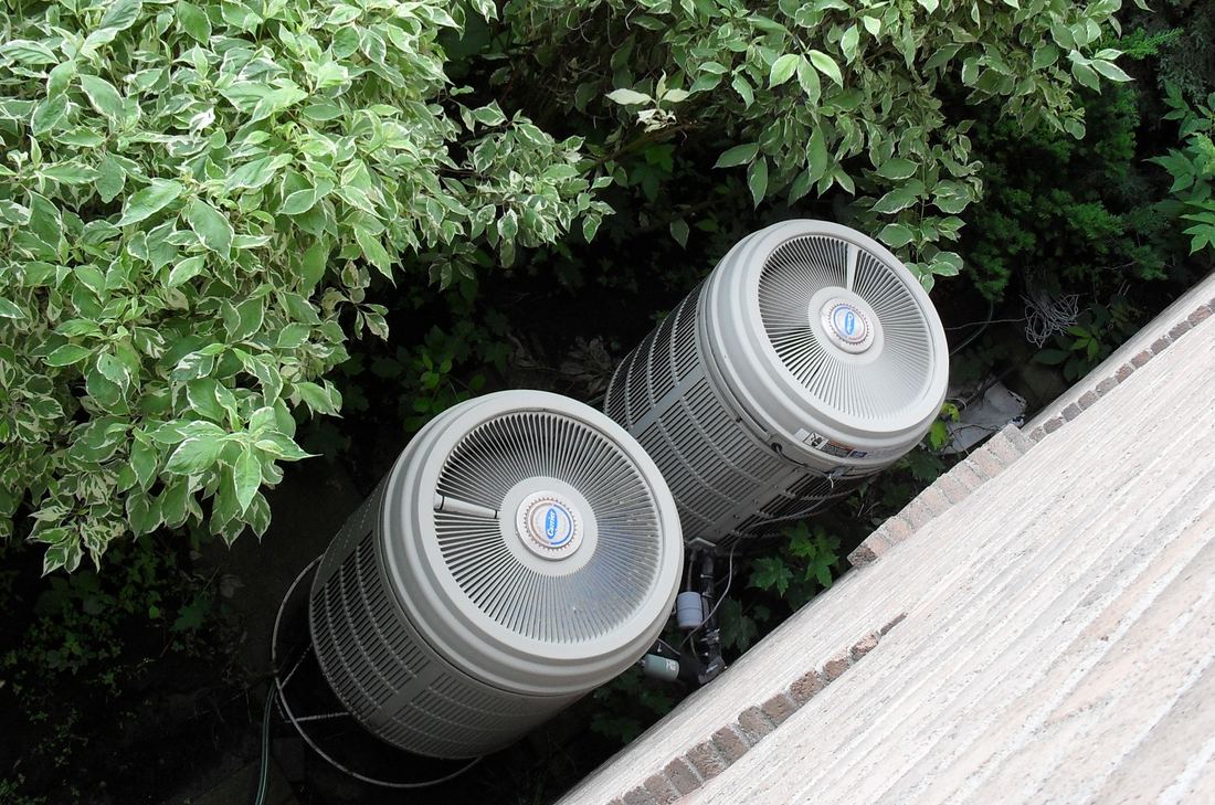 Two round outdoor heat pump units beside a house