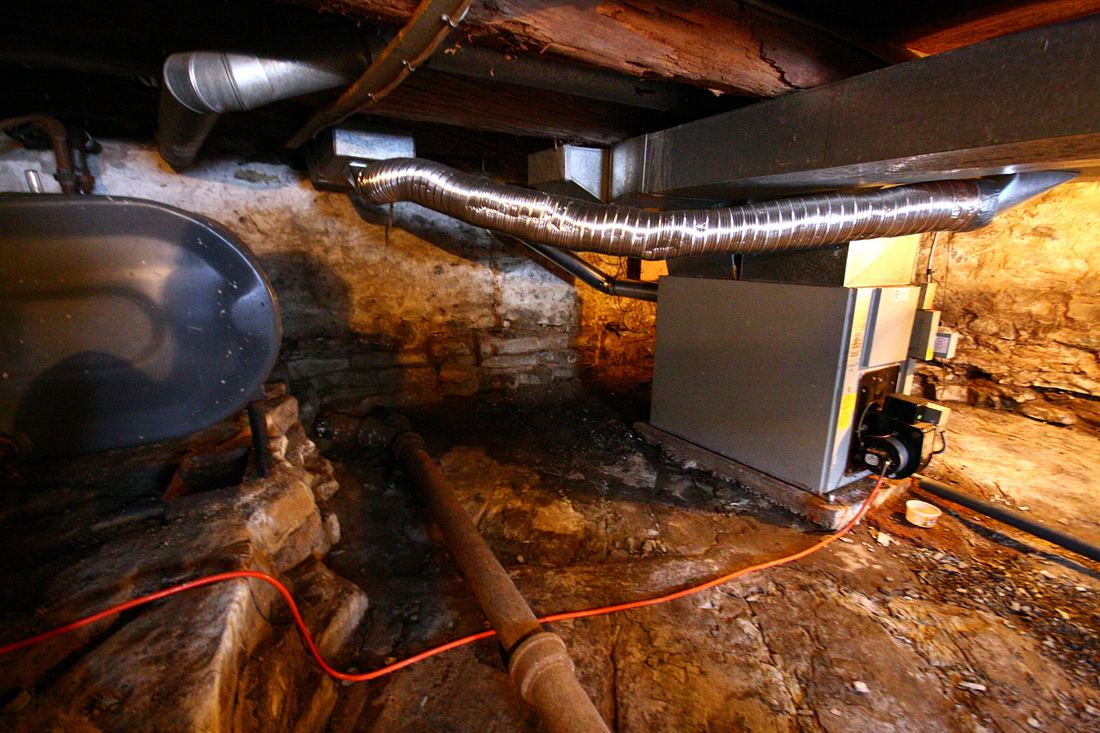 A furnace in a crawl space with flexible ducts running from it