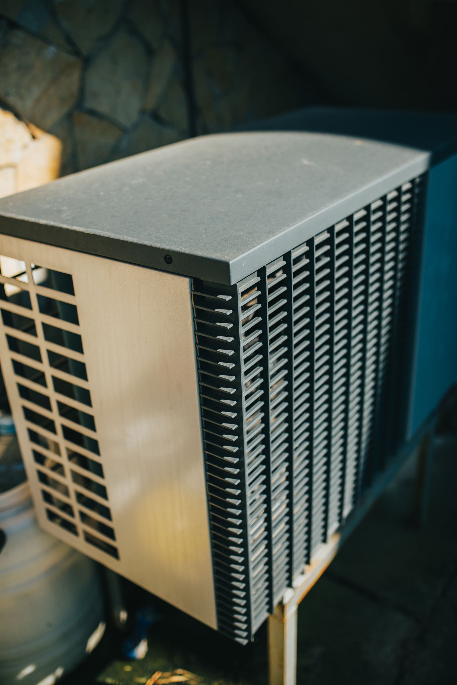 An outdoor air conditioner unit beside a house wall in a garden