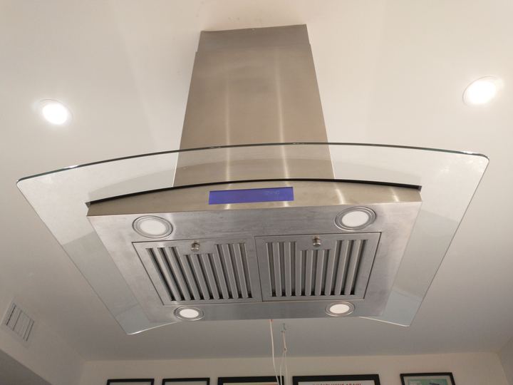 A stainless steel and glass range hood above a kitchen cooktop